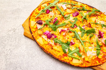 Hot homemade Hawaiian pizza on wooden board on stone background close up.