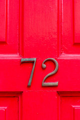 House number 72 with the seventy-two in bronze on a bright red door