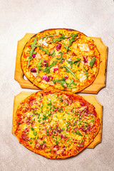 Hot homemade Hawaiian and Salami pizza on wooden board on stone background top view.