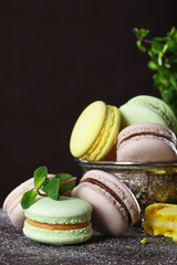 Macaroons cakes in vintage dishes on a brown background. Still life concept
