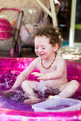 Redhead toddler splashing water in a pool
