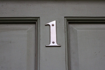 House number one with the 1 in elegant silver metal on the middle cross of a wooden house door