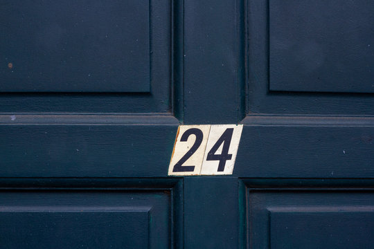 House number twenty four with the 24 on the middle cross frame of a panelled wooden house door