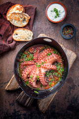 Traditional Greek octopus braised cooked with tomatoes and herbs in ouzo sauce with tzatziki as top...