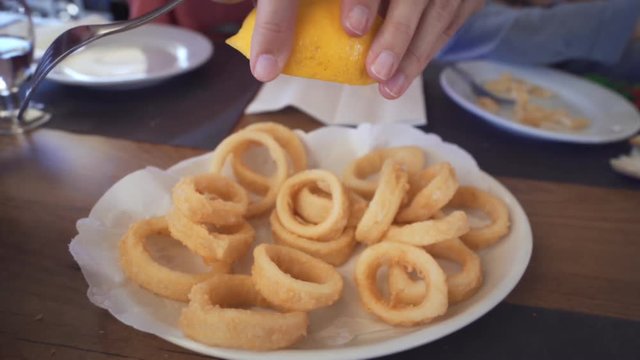 Spanish tapas: Adding lemon juice on Roman-style squid or fried calamari. Typical spanish food
