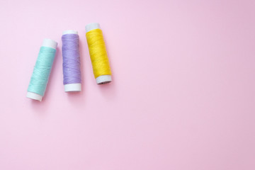 Colored sewing thread on a pink background