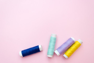 Colored sewing thread on a pink background