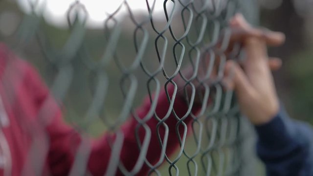 defocused couple hands touching through net.Love,prohibition, impossible love