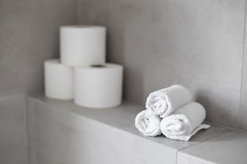 Fototapeta na wymiar Rolled white towels and toilet paper rolls at restroom