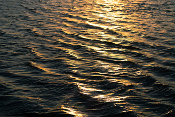 Water texture. Water reflects the rays of the setting sun. Beautiful lake, river, sea.
