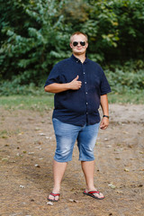 positive fat guy in sunglasses in a summer park