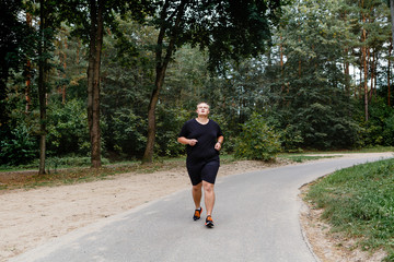 very fat guy runs in the park in summer