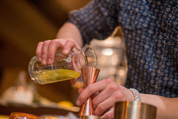 barman preparing cocktai and  pours liquid into the jigger in a cocktail bar