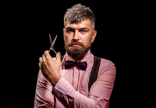 Barberman with scissors. Portrait of handsome male barber holds sharp scissors. Man on black background isolated
