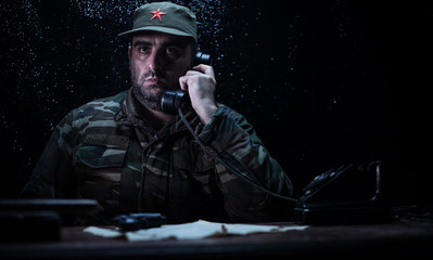The evil dictator sitting on table. Angry communist general sitting at headquarter or Cuban...
