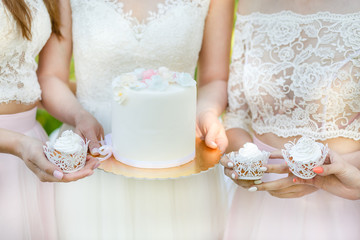 Bride holding a beautiful wedding cake. Bride and bridesmaid hold cakes at the wedding
