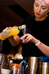 Bartender pours liquid into the jigger. Female bartender preparing cocktail in a cocktail bar