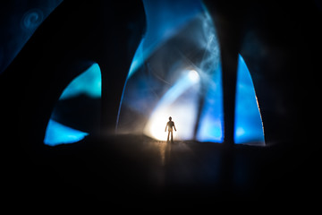 Artwork decoration. Silhouette of a man standing in the middle of the road on a misty night with giant high heel women shoes. Women power or women domination concept.