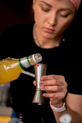 Bartender pours liquid into the jigger. Female bartender preparing cocktail in a cocktail bar