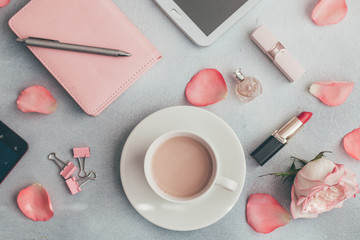 Women's workplace notebook, computer tablet, cup of coffee, flowers, lipstick, perfume.