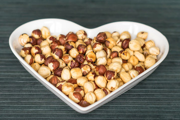Nuts arranged in heart  on background. Healthy Food image close up hazelnuts. Love Texture on top view