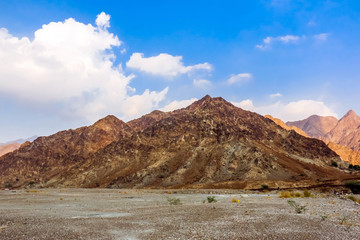 Fototapeta na wymiar Geological landscape of Jabal Jais characterised by dry and rocky mountains, Road between mud mountains in Ras Al Khaimah, United Arab Emirates