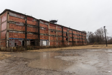 Fototapeta na wymiar Large abandoned factory on edge of depressed urban area