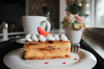 Millefeuille Napoleon with coffee in cafe. Exquisite dessert with fresh berries on white background. French Vanilla Raspberry Mille-feuille on the dish