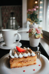 Millefeuille Napoleon with coffee in cafe. Exquisite dessert with fresh berries on white background. French Vanilla Raspberry Mille-feuille on the dish