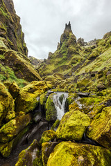 Amazing rock formations in the end of Thakgil canyon in Southern Iceland, the rapids of Kerlingardalsa river wash rocks covered with green moss.