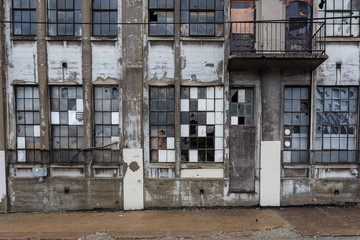 Grungy exterior of abandoned factory with checkered windows