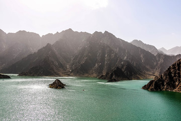 Geological landscape of hatta dam characterised by dry and rocky mountains and lake between scenery mountains, water reservoir Between hills in Dubai, United Arab Emirates