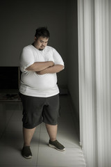 Fototapeta na wymiar Overweight man looks sad near the window