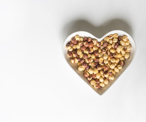 Nuts arranged in heart  on background. Healthy Food image close up hazelnuts. Love Texture on white grey table top view