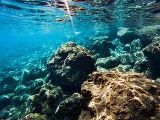 Texture of stones, earth, seabed with coral reefs and algae under blue-green water, underwater sea view, ocean in a tropical resort. Mediterranean sea. Greece. Background
