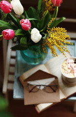 March 8,Easter,Mother's day concept /tulips in the vase,cup of coffee with marshmallows,open book ,glasses
