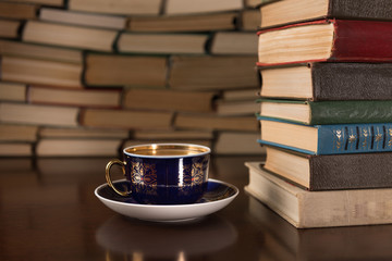 cup of tea and many books on a wooden table