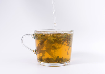 pouring hot water to the glass cup with tea, isolated on white background