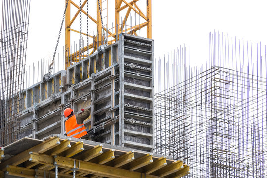 Construction Worker In A Red Vest Puts Armature On A Residential Building Under Construction