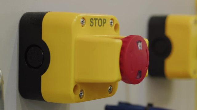 Palm pressing red stop button, hand reset emergency signal. Stopping industrial process. Pushing alarm button, turning it back. E-stop button on factory production. Press of red buzzer, distress siren