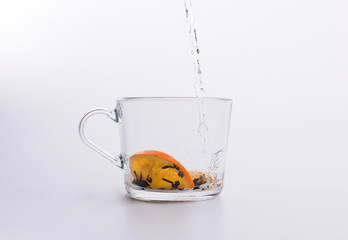 Water pouring into glass cup with black tea and lemon Isolated on white background
