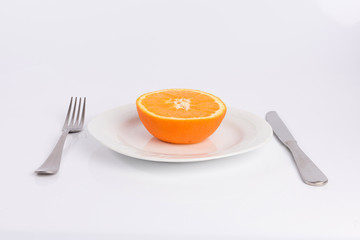 half an orange on a plate isolated on white background