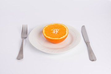 half an orange on a plate isolated on white background
