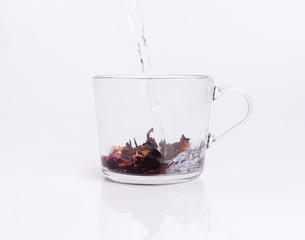 Pouring hot water to the glass cup with hibiscus tea, isolated on white background