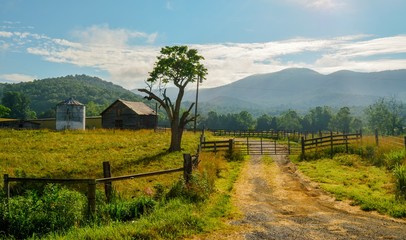 scenic Farm land with tree, wood fence, barn, silo, grass, mountains © JMP Traveler