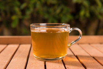 Tasty herbal tea in glass cup on the table, summer leisure