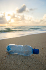 Fototapeta na wymiar Used plastic water bottle washed up on the shore of a tropical beach, highlighting the worldwide crisis of plastic pollution on even the most remote islands