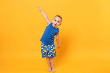 Smiling fun kid boy 3-4 years old wearing blue beach summer clothes isolated on bright yellow orange wall background, children studio portrait. People, childhood lifestyle concept. Mock up copy space.