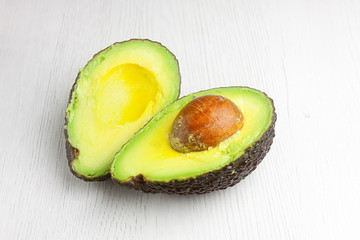 PRIMER PLANO DE AGUACATE ABIERTO SOBRE FONDO DE MADERA CLARA