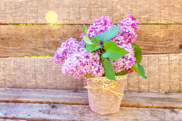Ecology nature springtime concept. Bouquet of flowers beautiful smell violet purple lilac in vase on rustic wooden background. Inspirational natural floral spring blooming garden or park